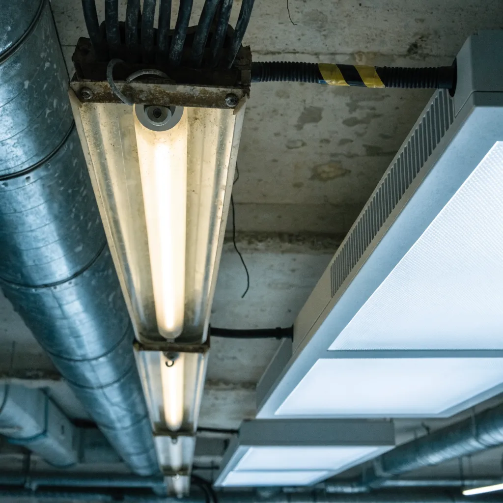 Tubes fluorescents anciens encore en place à côté d'un panneau LED installé en parallèle, illustration de la dépose non effective sanctionnée par la DGEC